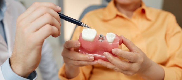 Close up of patient holding model of dental implant in Matthews