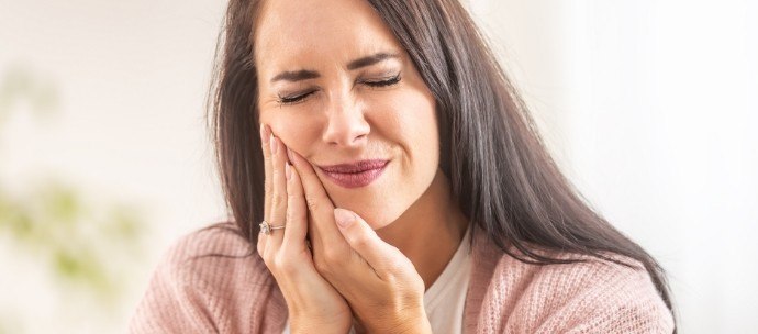 Woman in pink shirt rubbing her jaw in pain