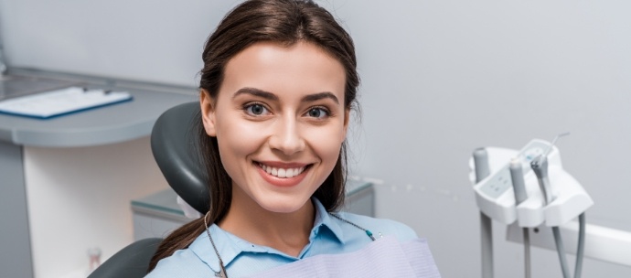 Female dental patient sitting in dental chair and smiling