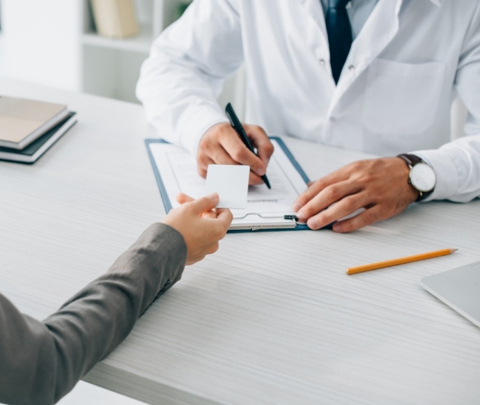 Handing dentist a card while they write on clipboard