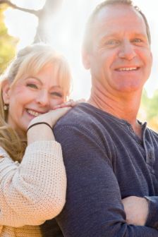 Man smiling with arms folded with woman behind him