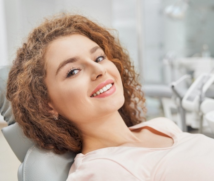 Female dental patient leaning back in dental chair and smiling