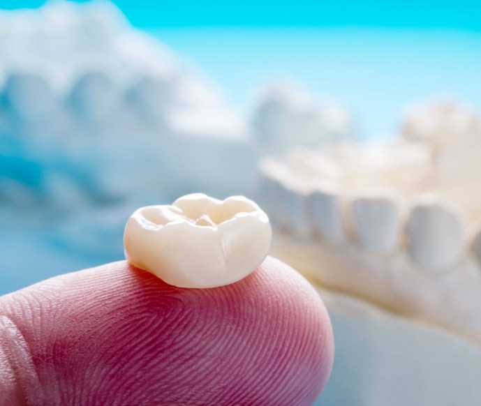 Finger holding a dental crown for restorative dentistry in Matthews