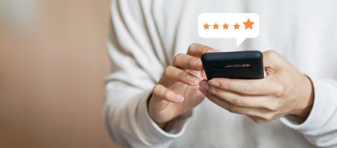 Person in white shirt leaving a five star review on phone