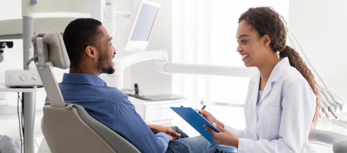 Female dentist speaking to male dental patient