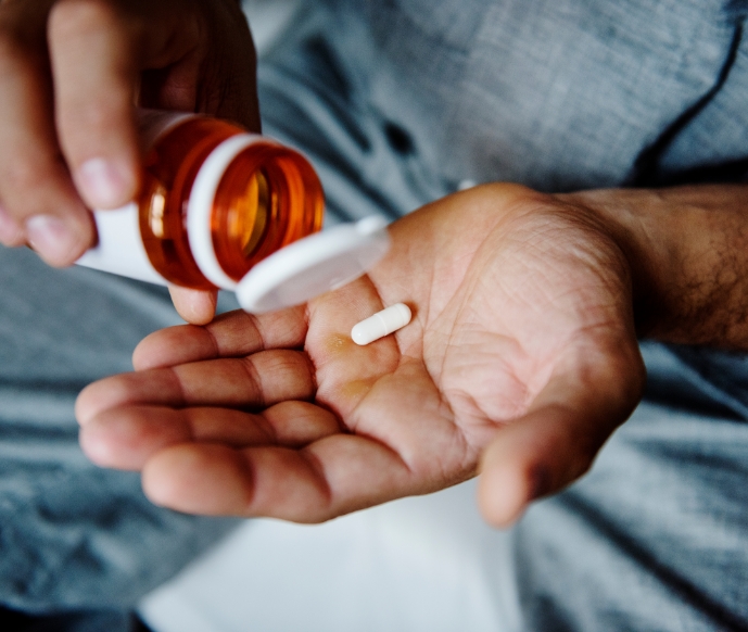 Hand holding a pill and other hand holding bottle