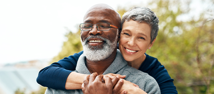 Smiling man being hugged by woman from behind